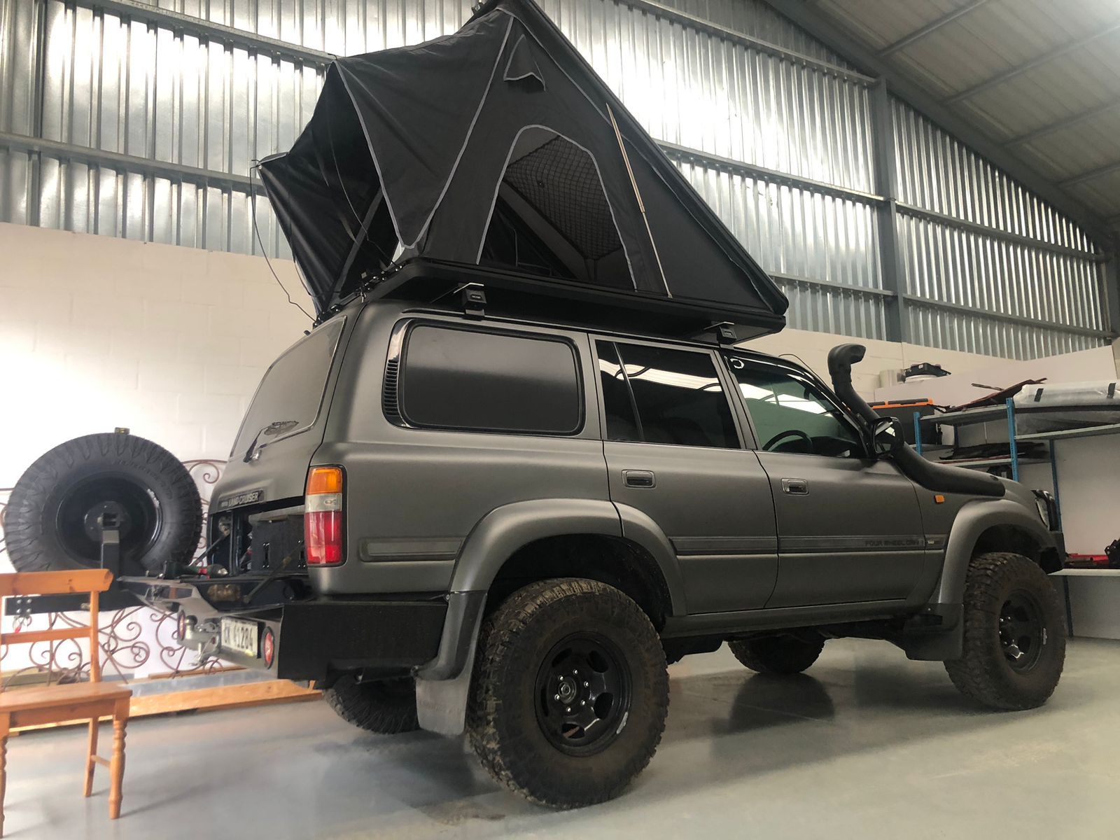 Rooftop tent open on a grey Land Cruiser inside the fitment bay