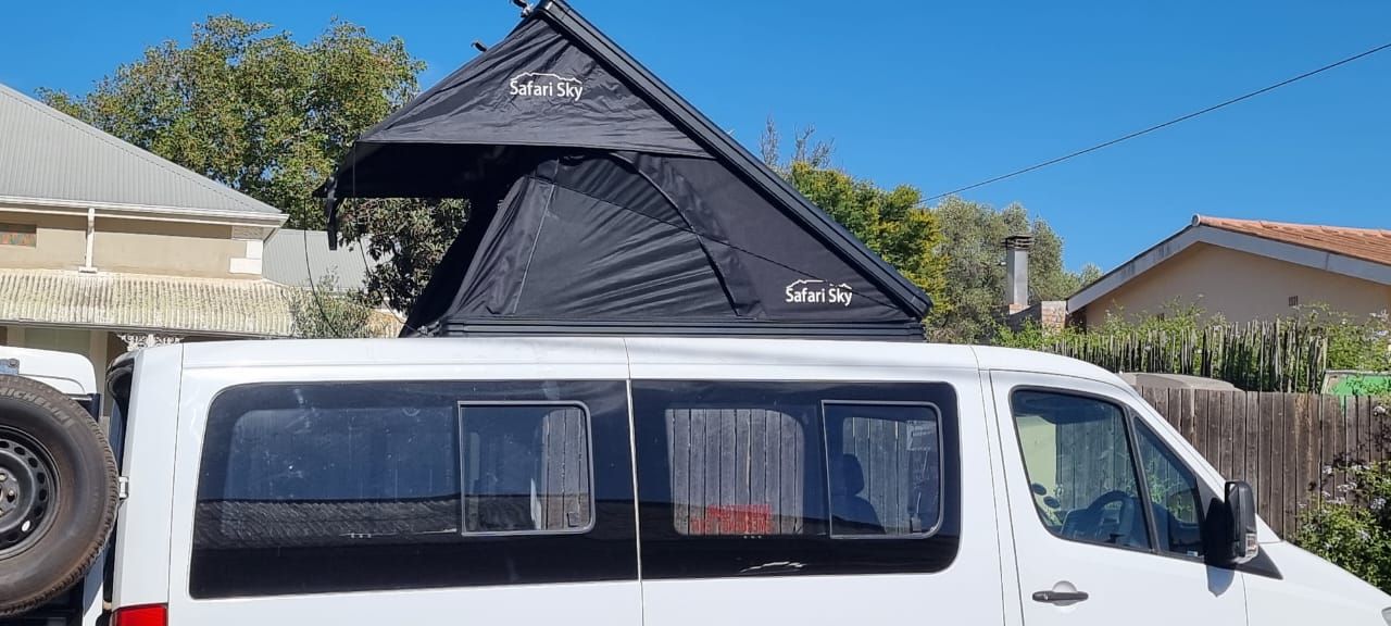 Safari Sky wedge tent deployed on the roof rack of a white passenger van