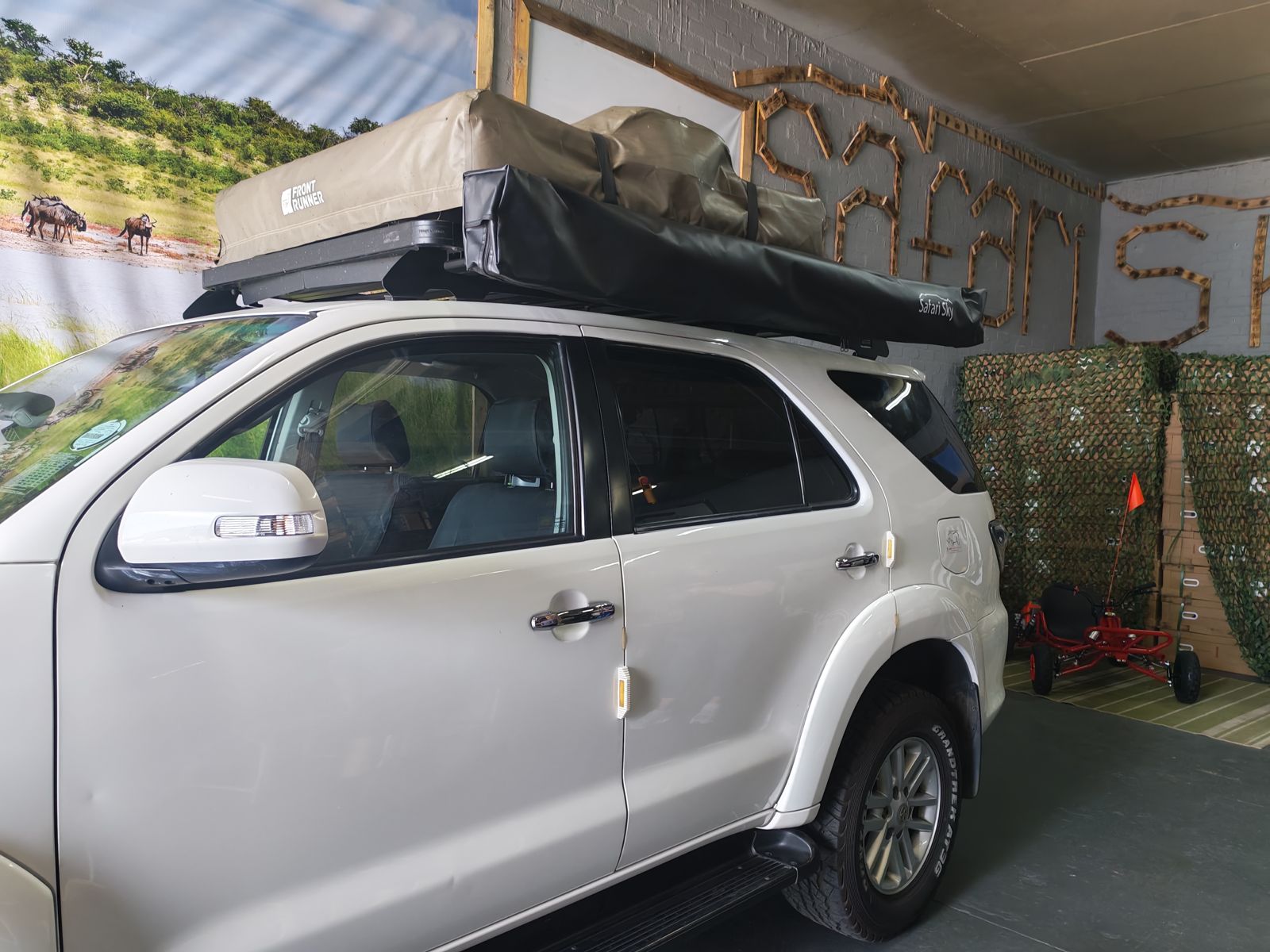 White SUV fitted with a rooftop tent and packed Safari Sky awning in the workshop